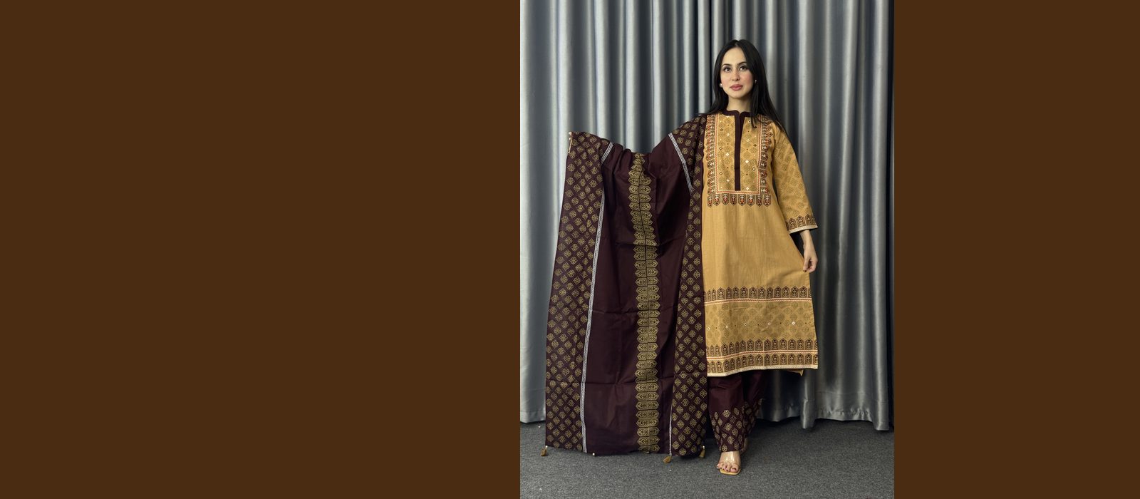 Model wearing a mustard three piece set with an ajrakh printed border