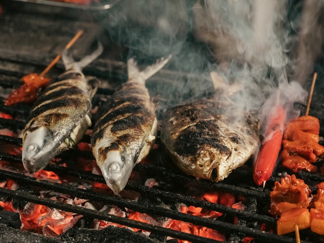 Whole fish cooking over an open charcoal grill