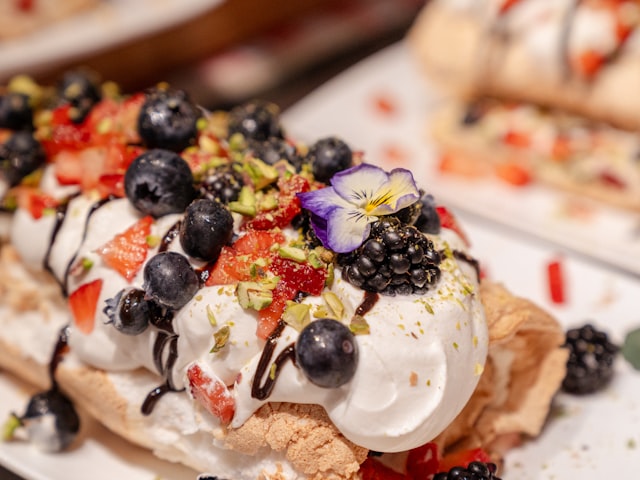 Meringue dessert with berries, cream and chocolate drizzle