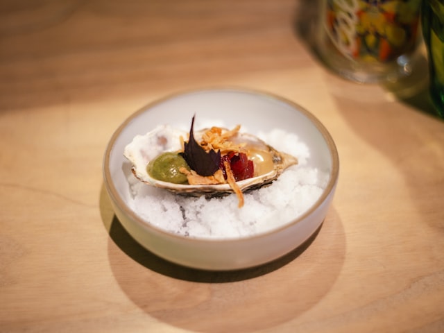 Grilled oyster topped with herbs and roe on crushed ice